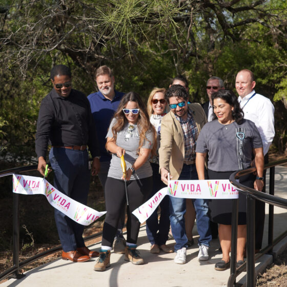 A group of people behind a large ribbon on the Madla Greenway trail in celebration of the trail's grand opening