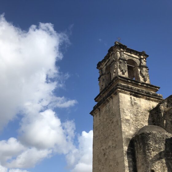 An upward view at San Jose Bell Tower with a blue sky and clouds in the sky