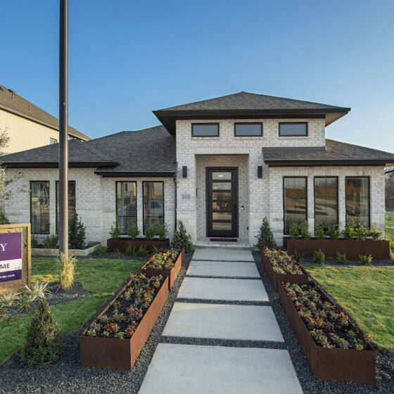 Perry Homes Model Home at VIDA, A Contemporary, Single Floor Model Home against a blue sky with green grass in the front yard