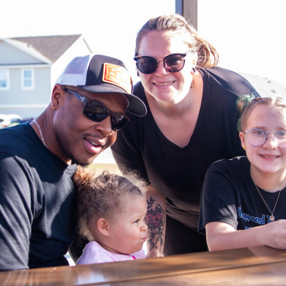 A family smlies while sitting at a park bench at VIDA san Antonio