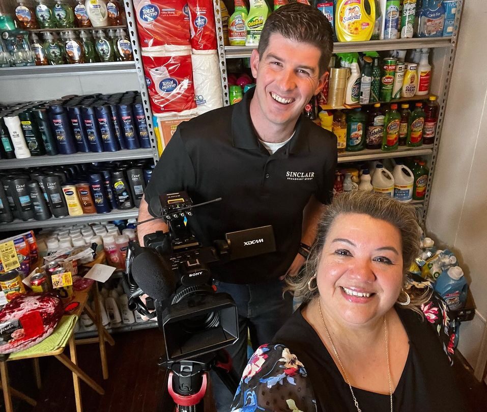 A cameraman and Brenda Anz pose for a photo in her pantry