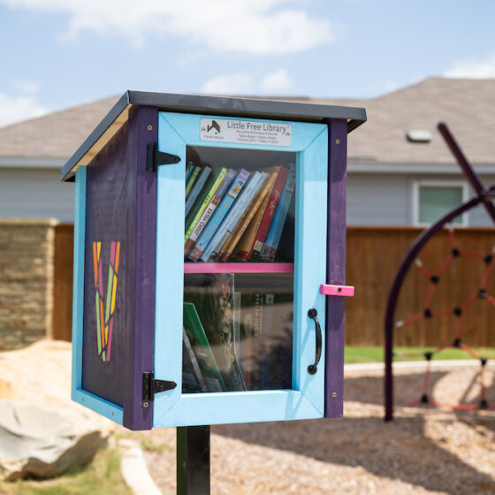 A colorful little free library full of books in a park