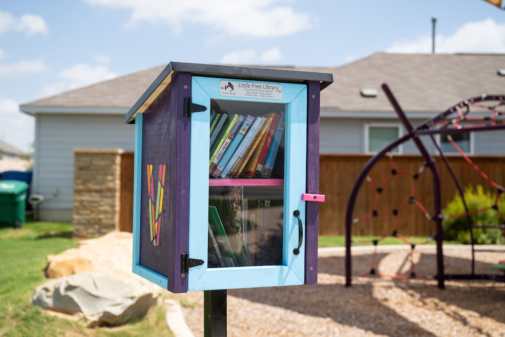 A colorful little free library full of books in a park