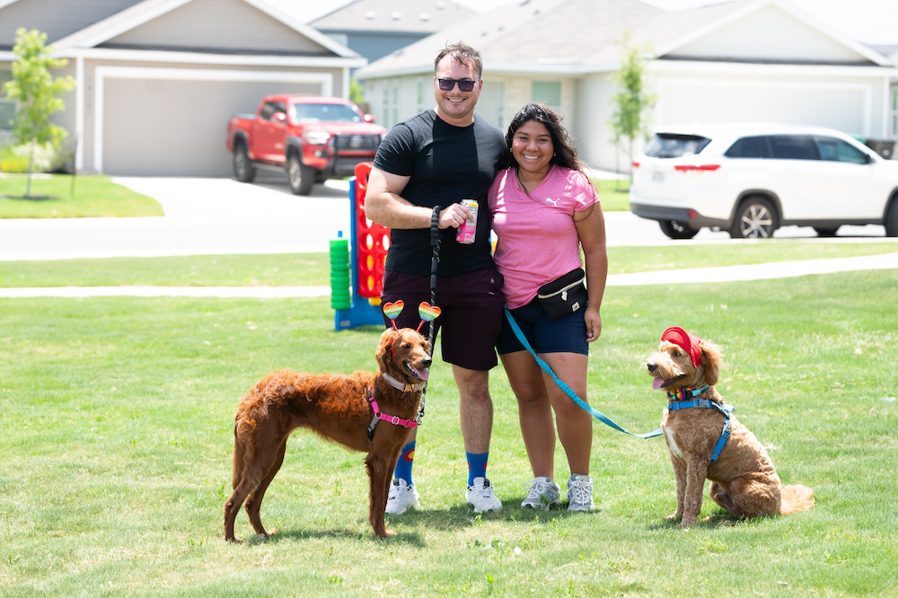 Two dogs and their pet parents stand in Ana Park