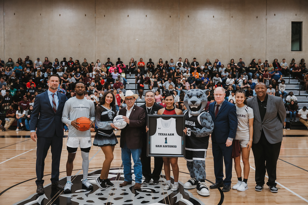 TAMUSA team and representatives on the basketball court presenting a jersey with 1 on it