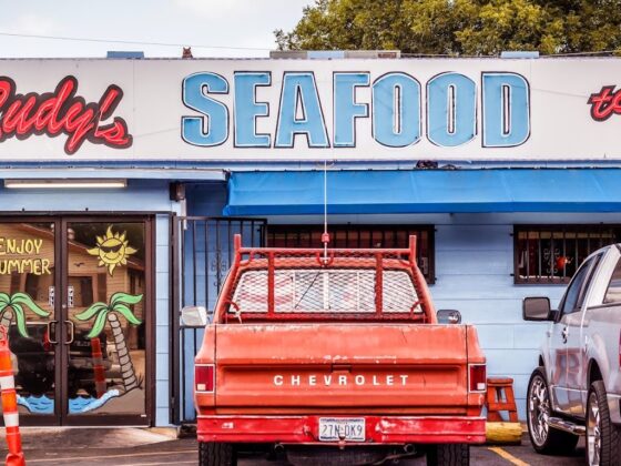 Storefront of Rudy's Seafood with a classic red Chevrolet truck parked in the front.