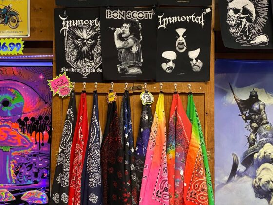 A collection of rock posters and fun technicolor bandanas in a store settinf