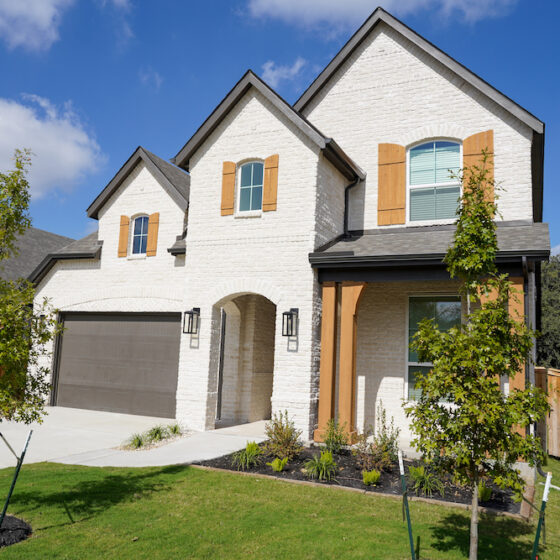 A white brick home with black and oak accents built by Perry Homes in the VIDA San Antonio neighborhood