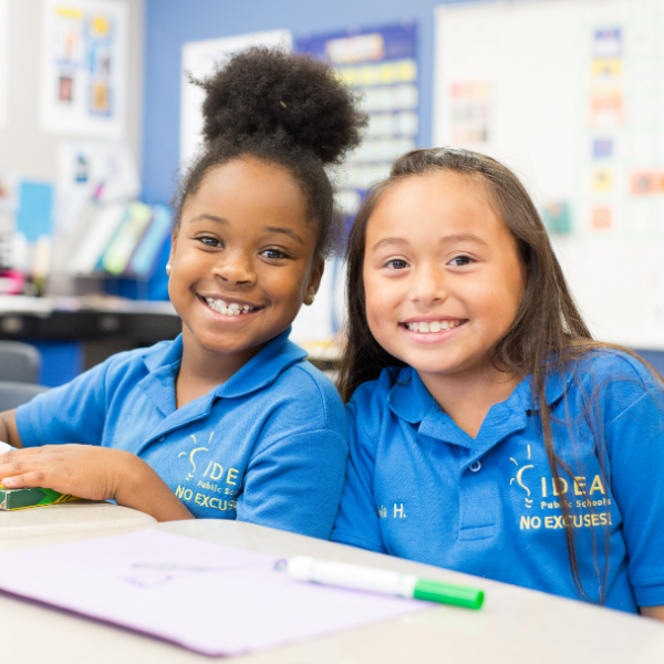 Two young children smile in school uniforms