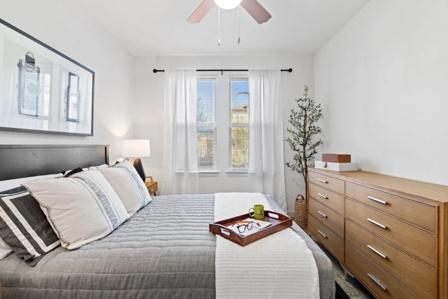 A cozy apartment bedroom with lots of natural lighting and neat bedspreads