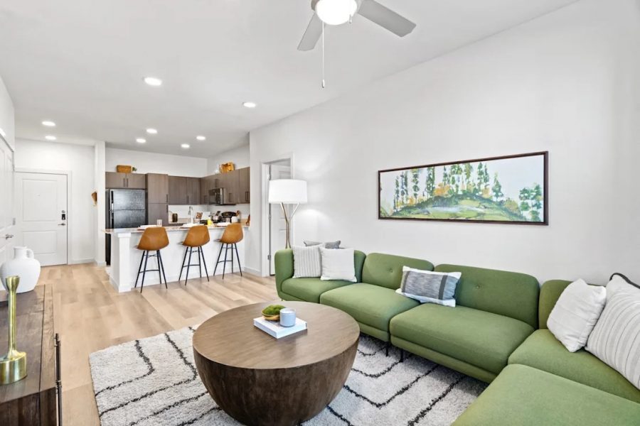 A living layout at Los Arcos with fun green couches and an open concept kitchen