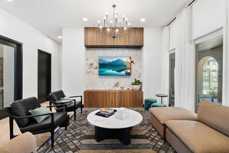 A modern apartment lobby with a chandelier and a tv.