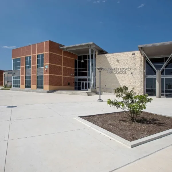 A geometric school facade to Southwest Legacy High School on a sunny day, with pavement in the forefront