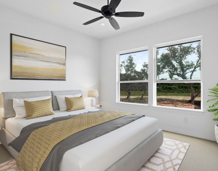 A bedroom with a large, double picture window, a ceiling fan, and a bed with yellow and gray bedding.